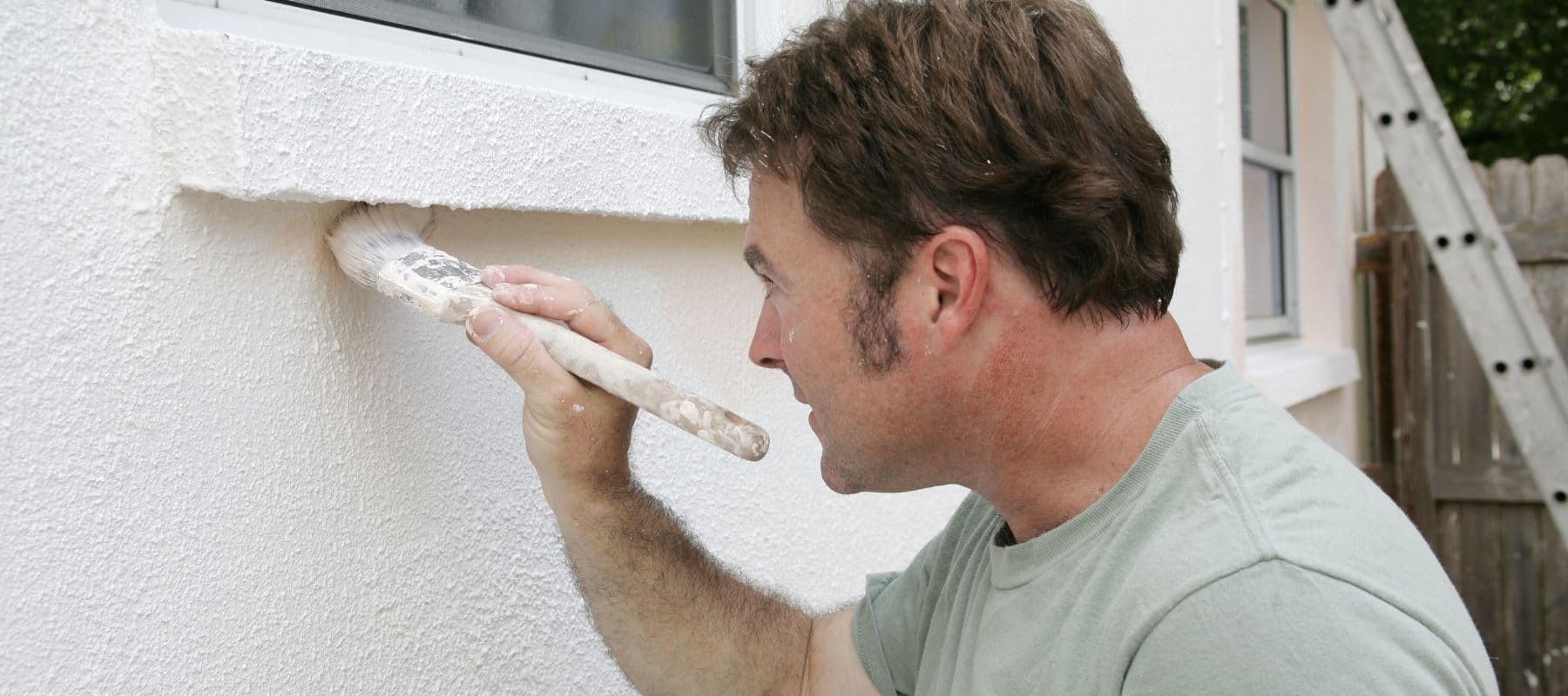 man painting exterior of home