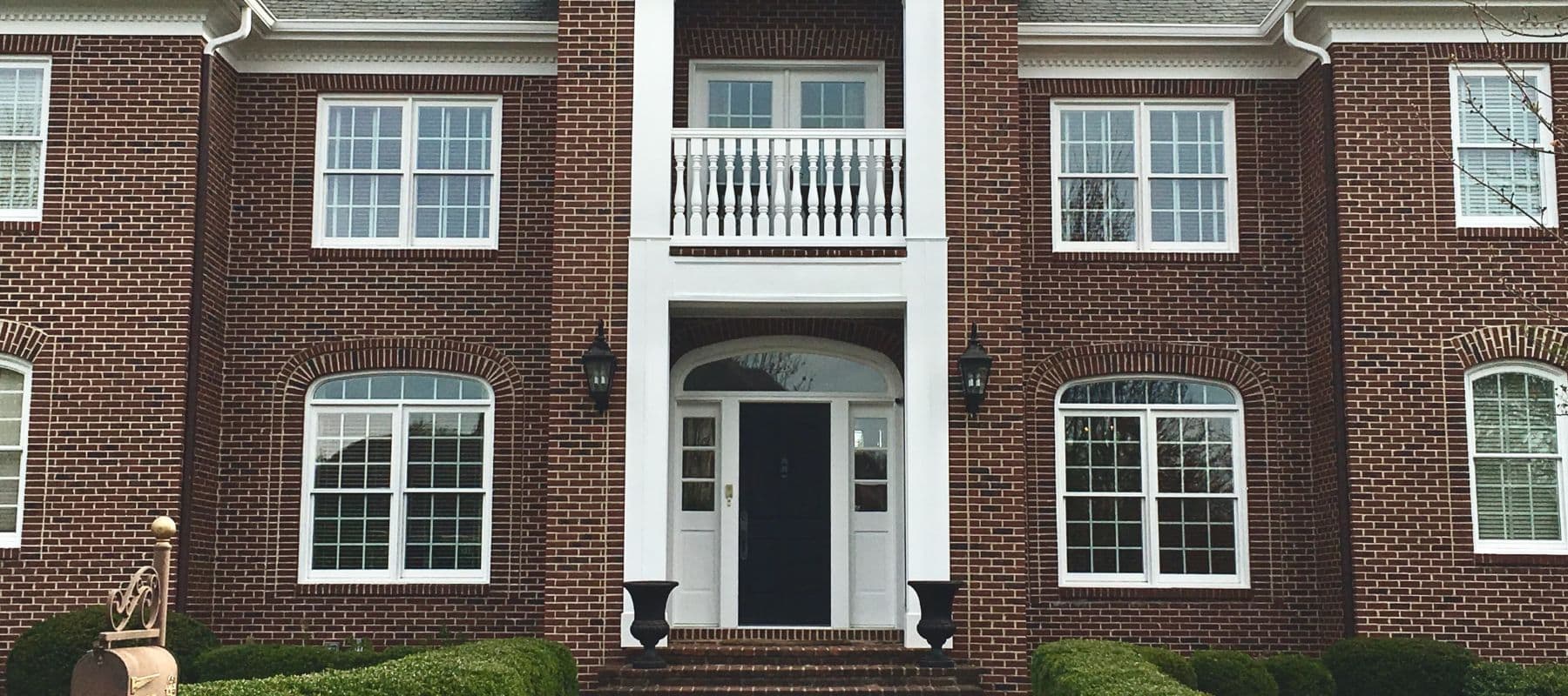 Brick home with white-trimmed windows and a small second-story balcony